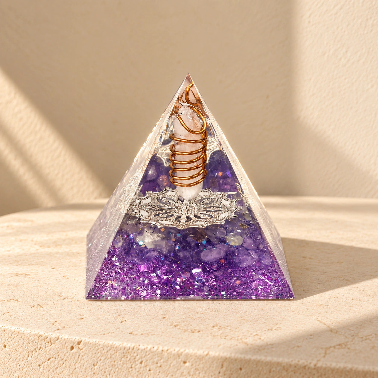 Intuition orgonite pyramid with amethyst, clear quartz and copper details on a warm ivory stone surface