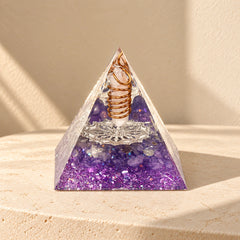 Intuition orgonite pyramid with amethyst, clear quartz and copper details on a warm ivory stone surface