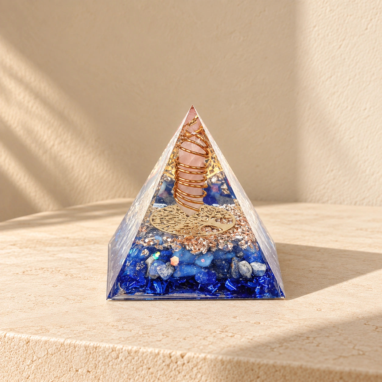 Rose quartz and lapis lazuli orgonite pyramid with opal and blue foil styled in warm natural sunlight