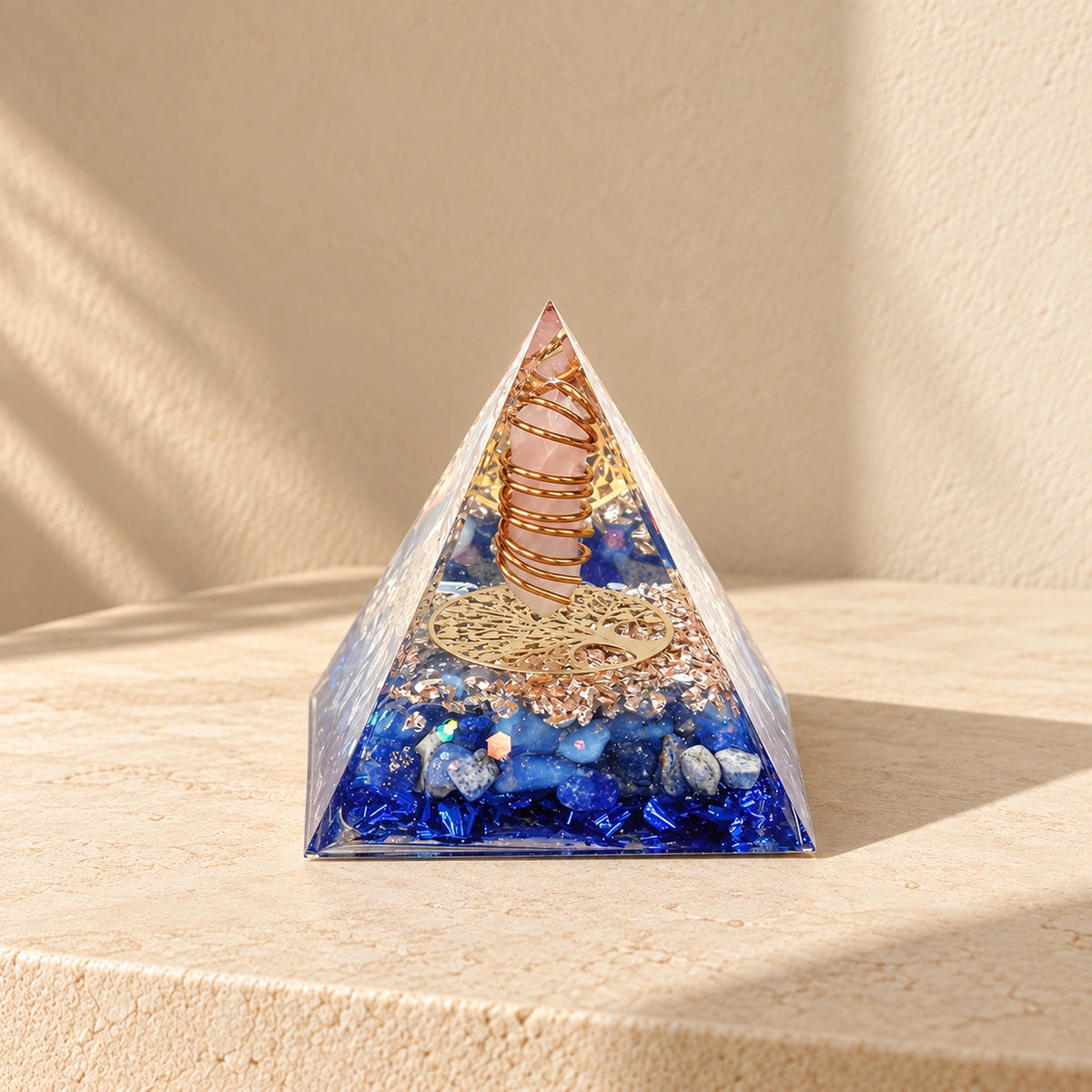 Rose quartz and lapis lazuli orgonite pyramid with opal and blue foil styled in warm natural sunlight