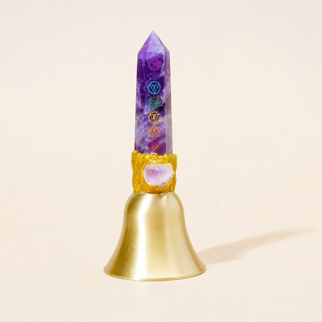 crystal point bell with chakra colors held by hand against a neutral background