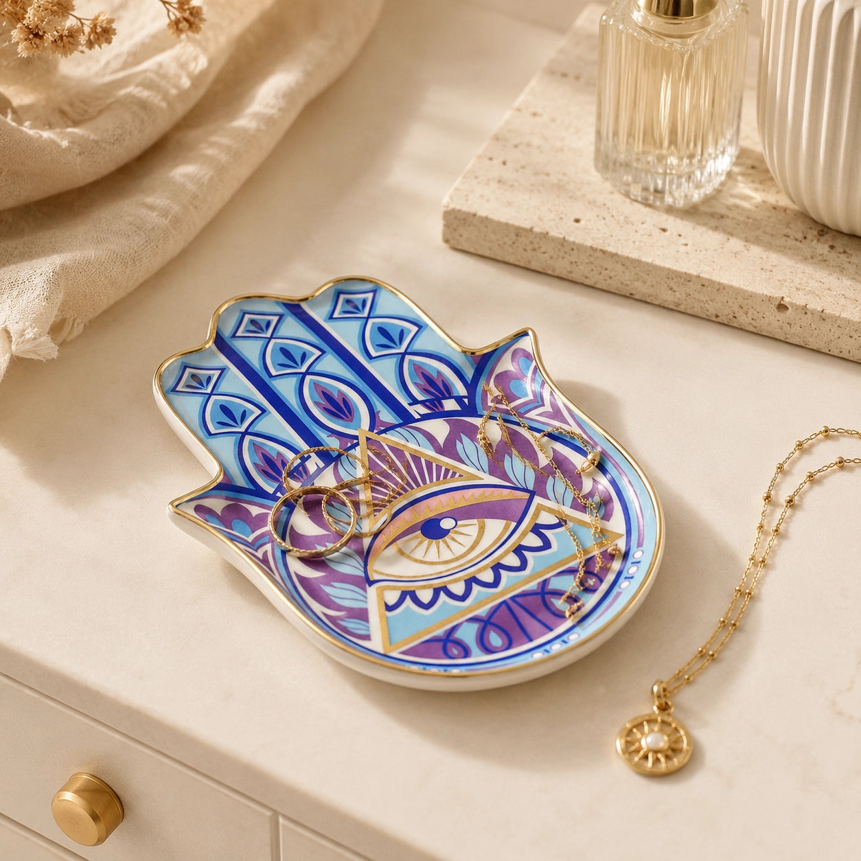 Hamsa evil eye ceramic trinket dish with blue, purple, and gold details on white background