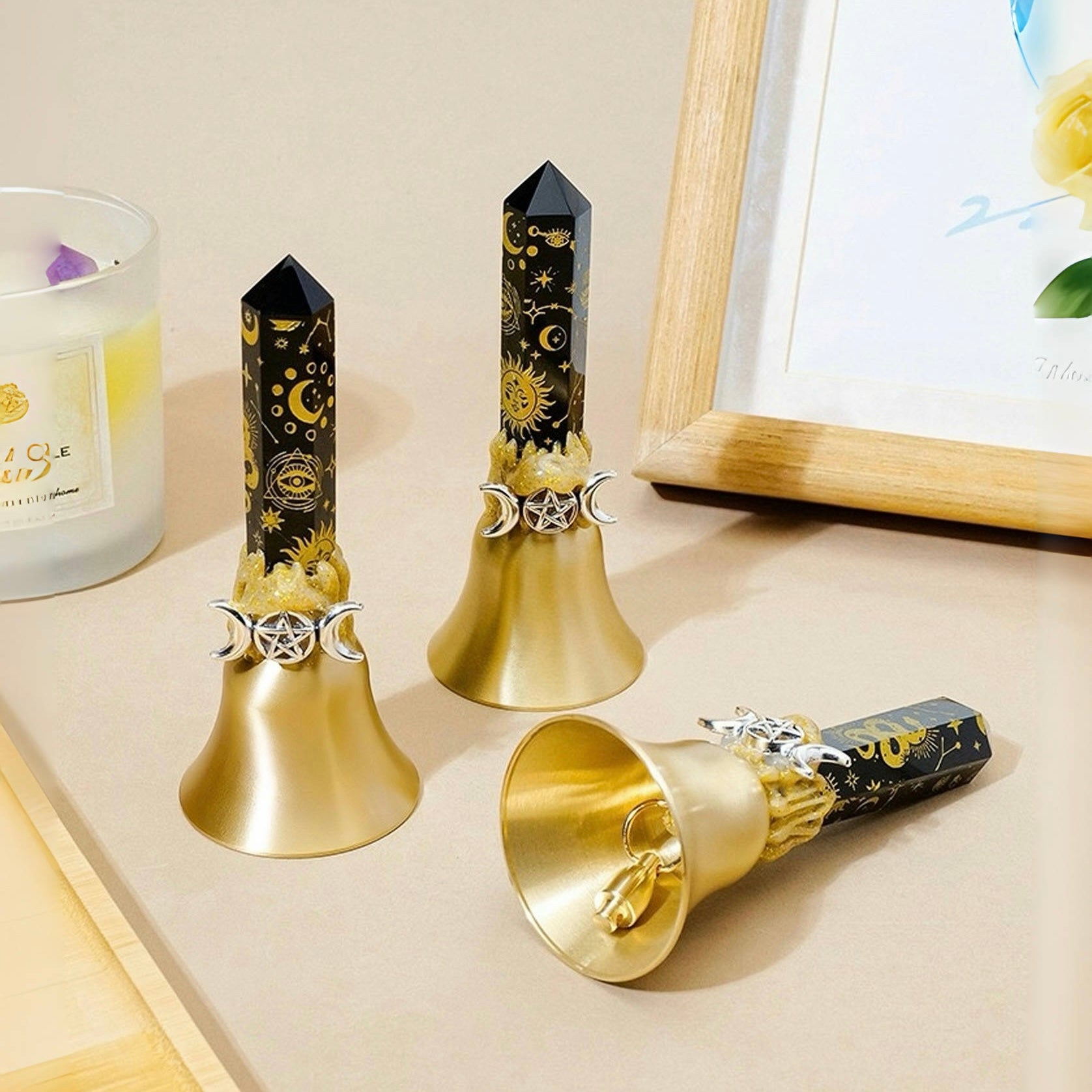 Black celestial obsidian crystal point bell with gold sun and star symbols, featuring a polished obsidian point mounted on a gold metal bell base.