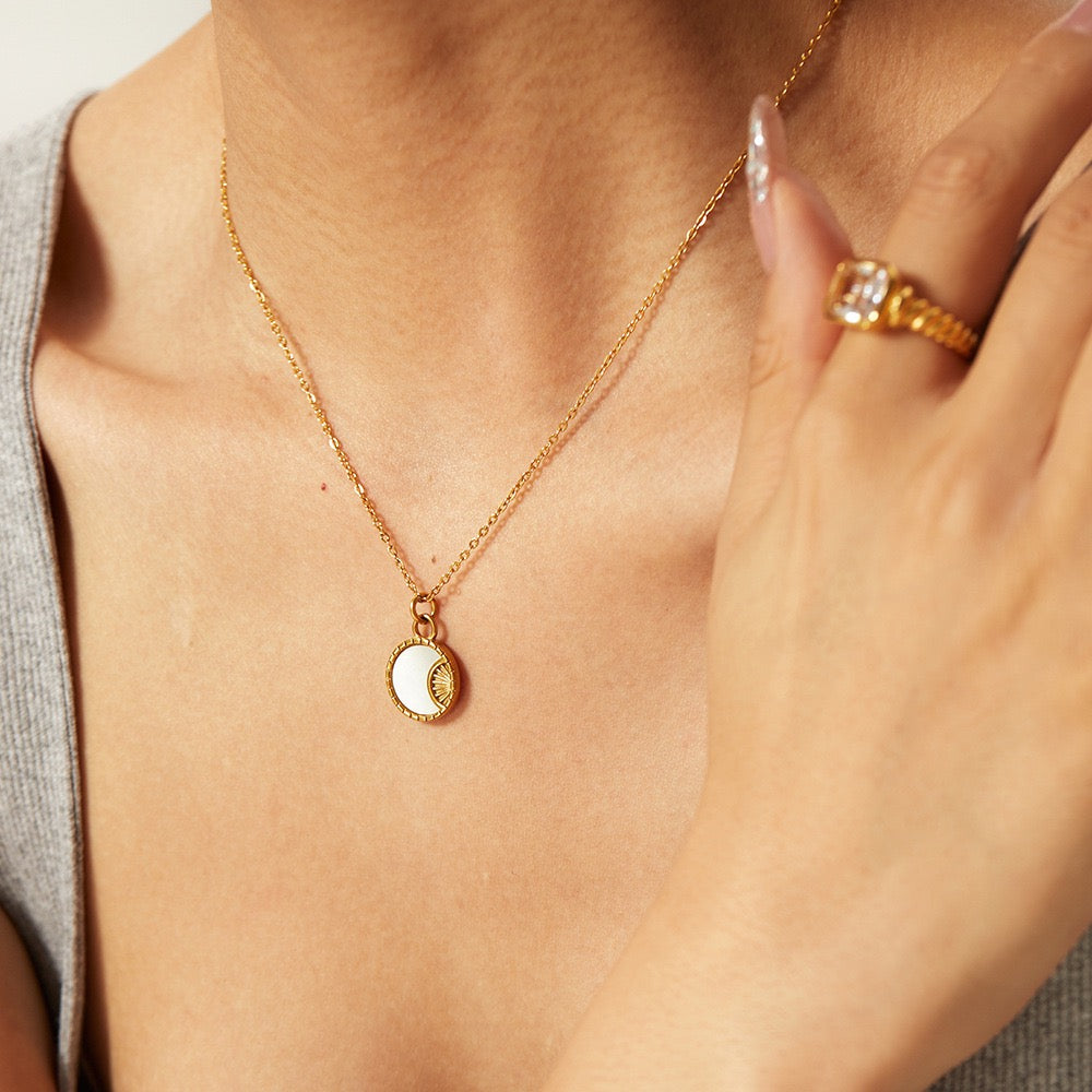 Gold necklace with a pendant worn by a person, close-up view.