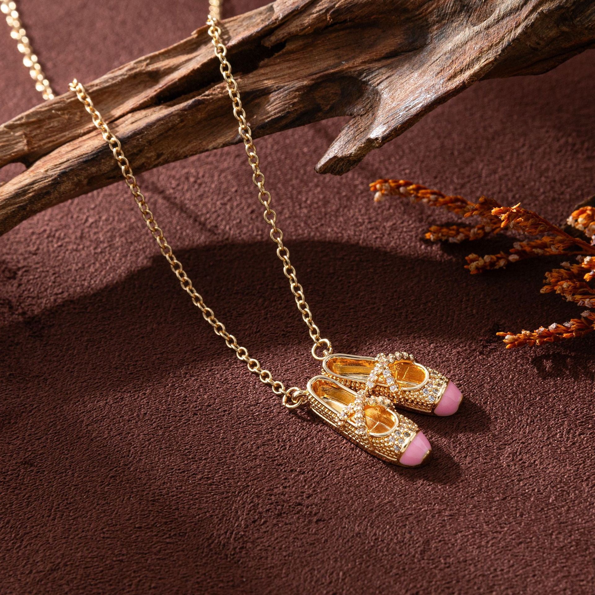 gold pink ballet slippers pendant necklace on a brown background, feminine symbolic jewelry
