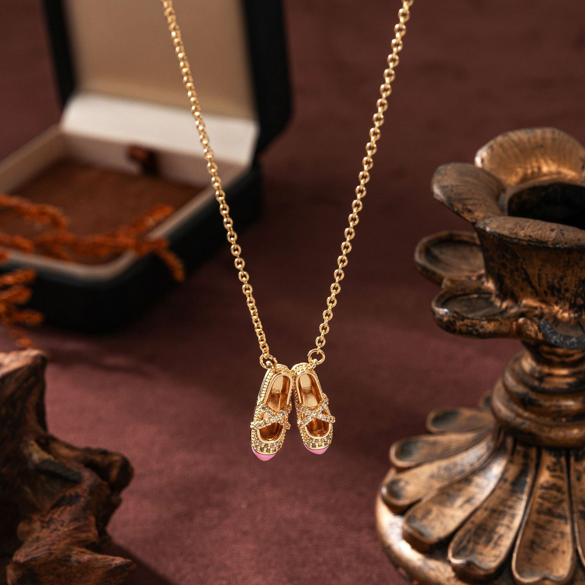 Gold necklace with ballet slipper pendants on a decorative surface