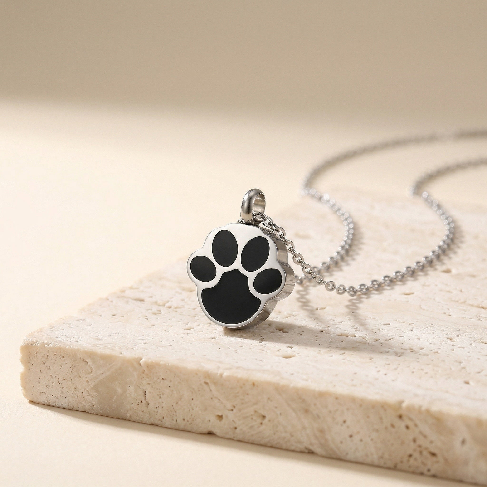 close-up of silver paw print pendant necklace for pet ashes or memorial keepsake