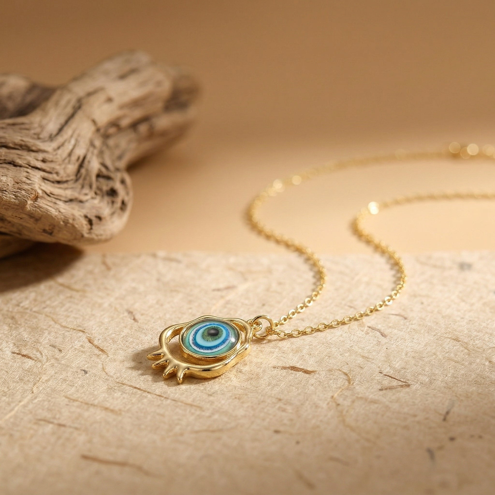 gold evil eye pendant necklace with turquoise blue eye detail on neutral surface