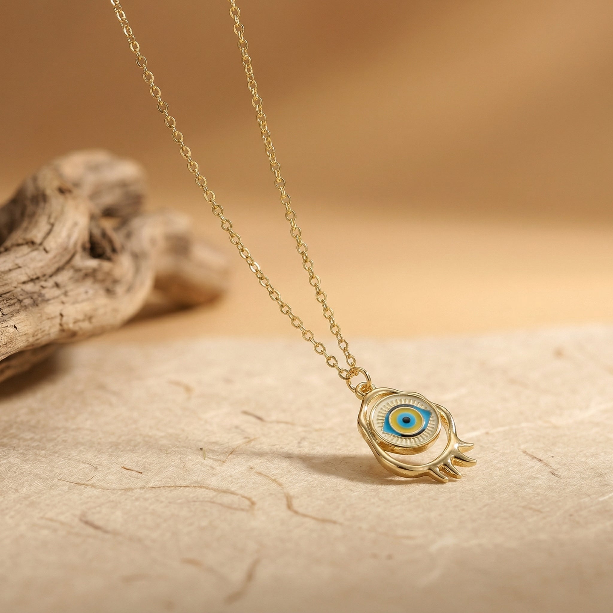 gold evil eye pendant necklace with blue and gold eye motif on neutral surface