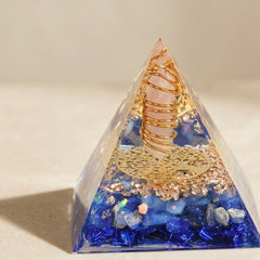 Emotional healing and inner peace orgonite pyramid with rose quartz point, lapis lazuli chips and copper coil on a neutral background