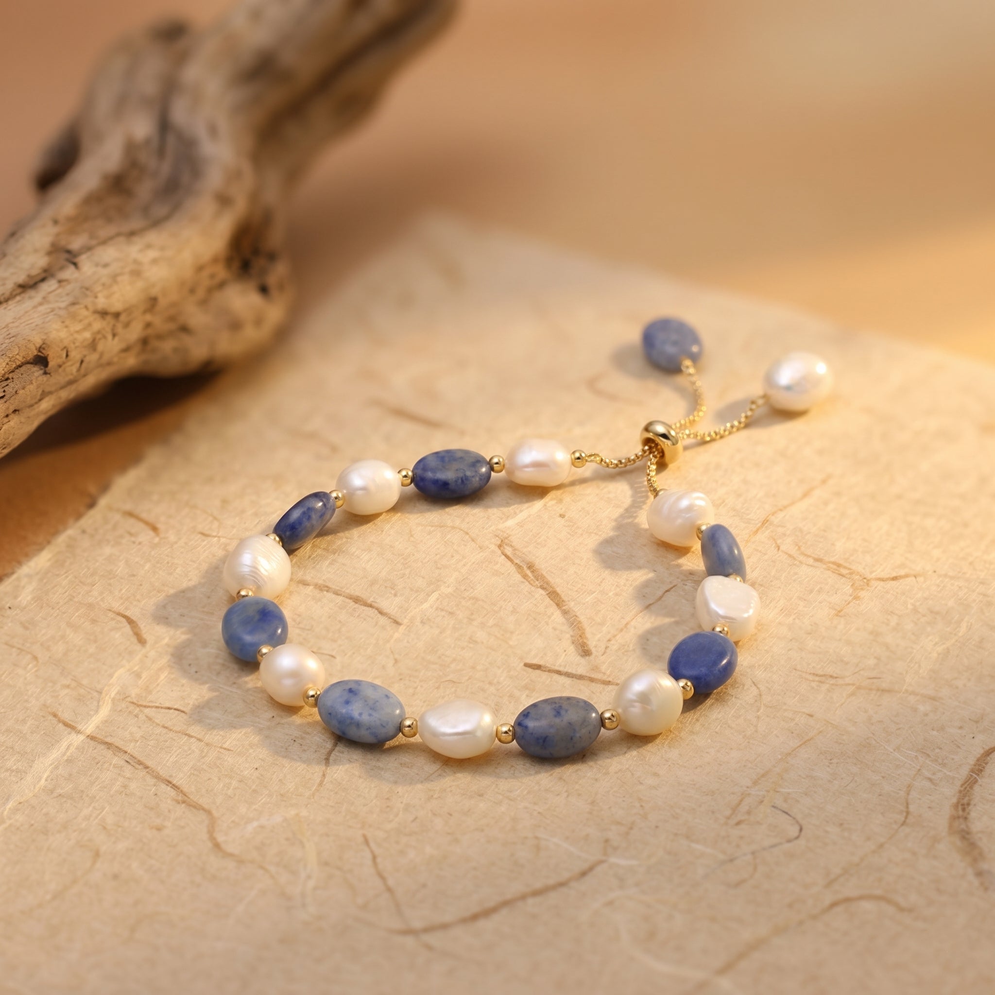 Blue aventurine and freshwater pearl bracelet styled on a warm beige surface with natural light