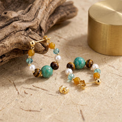 tiger eye and turquoise earrings styled with driftwood and gold accents for abundance energy