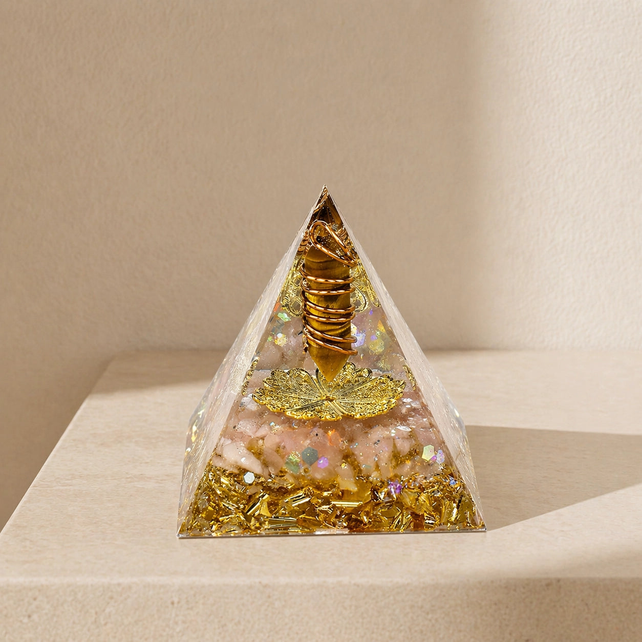 Abundance and wealth manifestation orgonite pyramid with tiger’s eye point, citrine chips, copper coil and gold details on a neutral background
