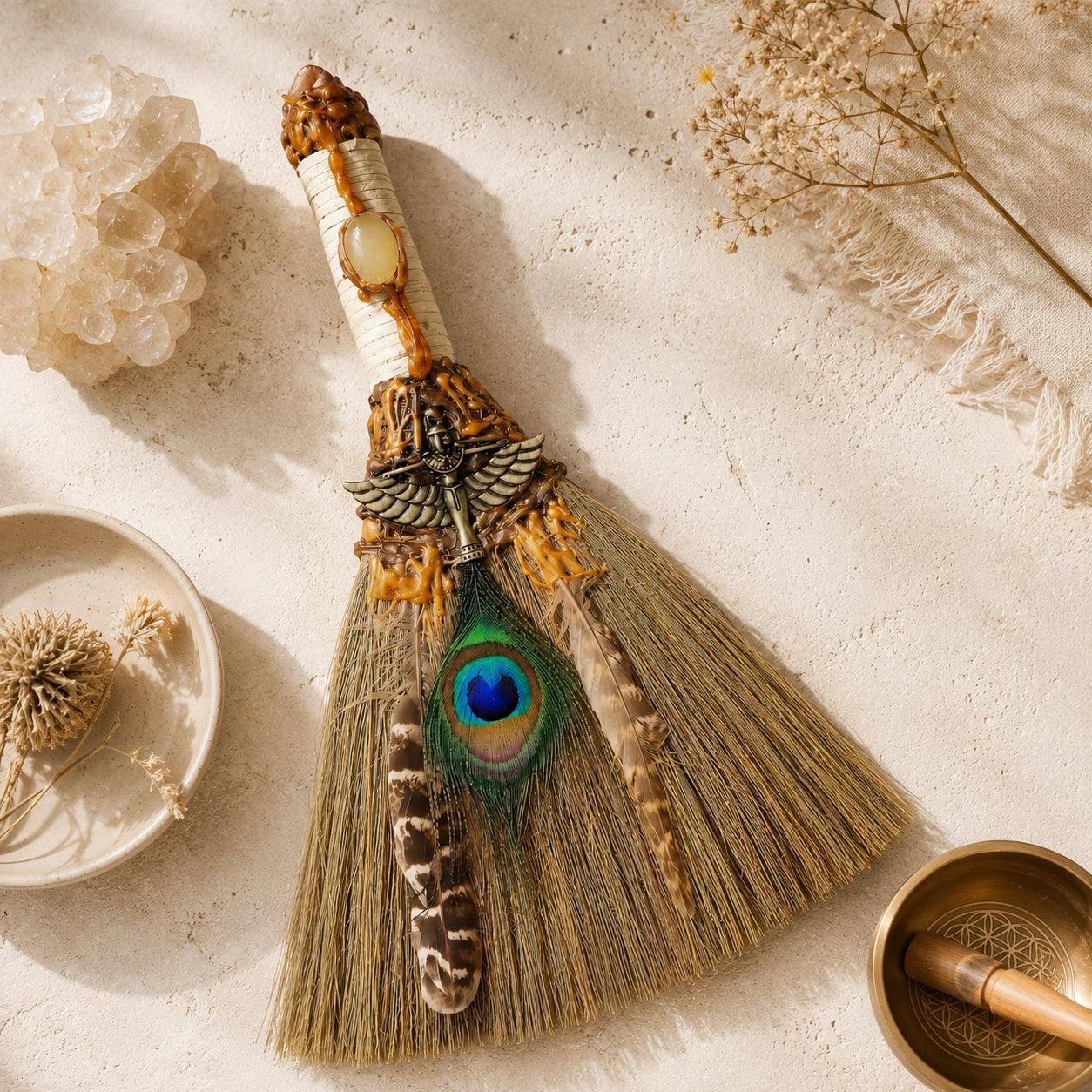 Handmade peacock feather witch broom for smoke-free energy cleansing styled flat with crystals and a singing bowl