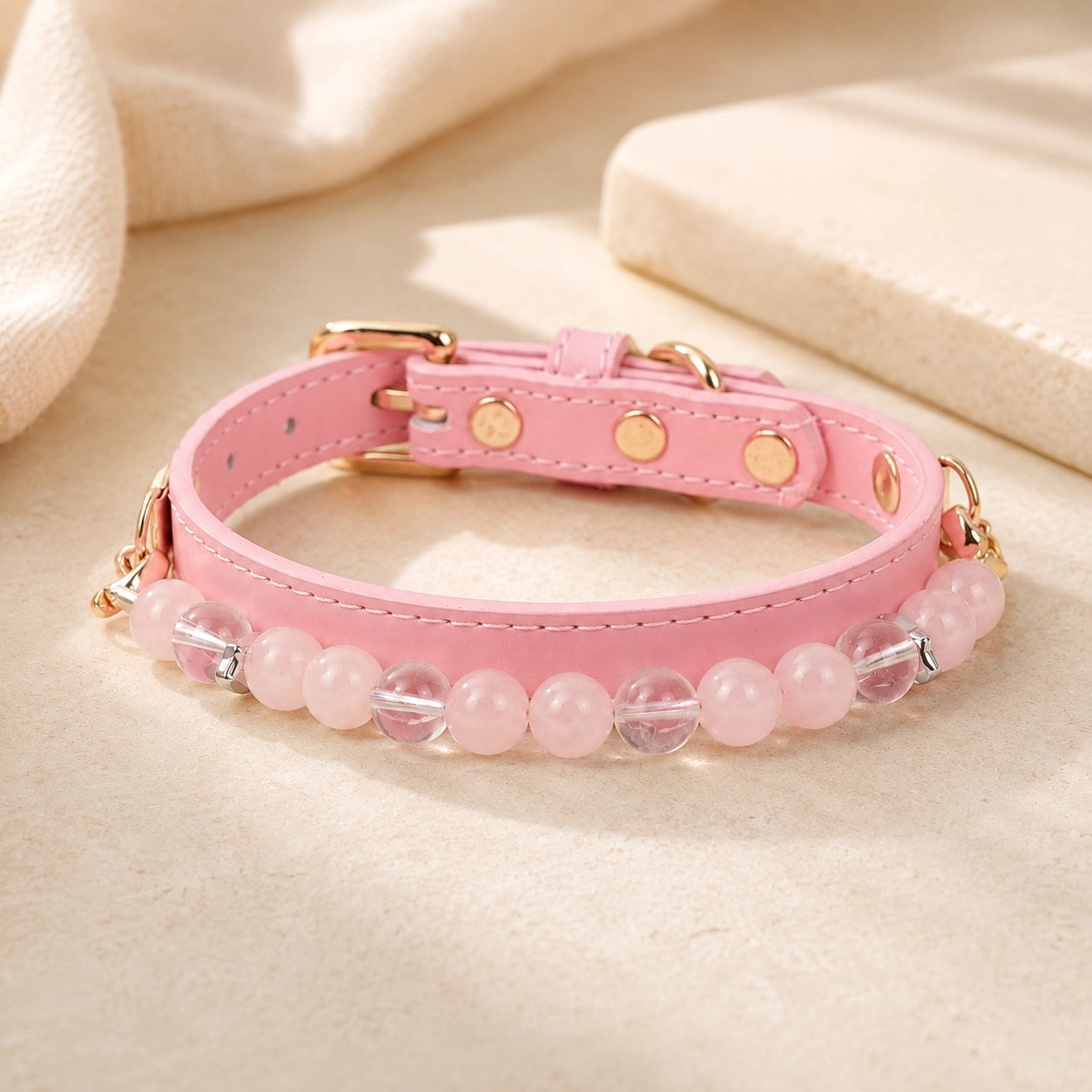 Adjustable pink rose quartz and clear quartz dog collar on a warm cream background