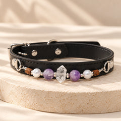 Black adjustable PU leather dog collar with purple amethyst beads and natural clear quartz centerpiece on a cream stone stand