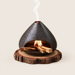 Fired Earth Brown ceramic Palo Santo and sage burner with burning wood and smoke on a natural wood slice