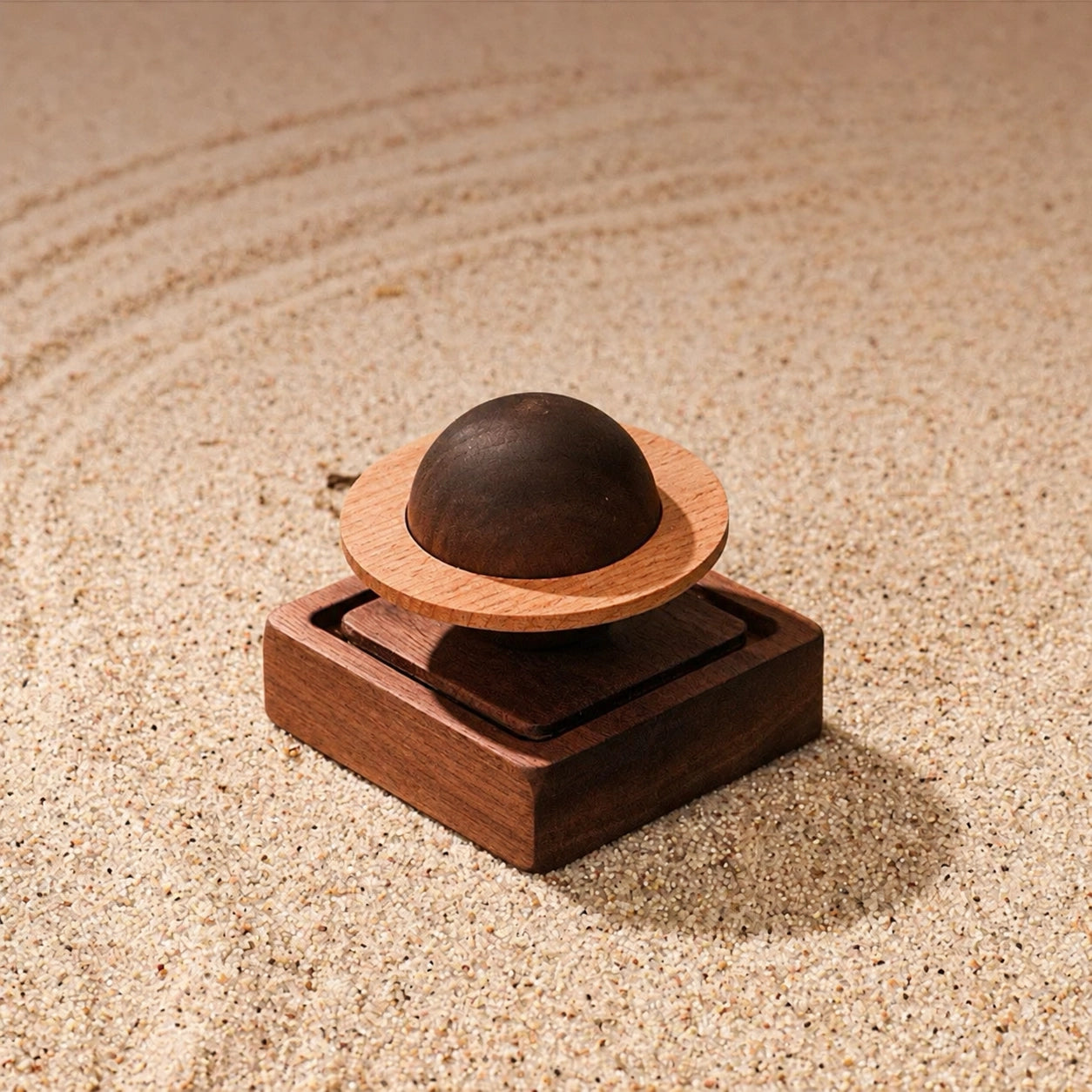 Wooden Saturn essential oil diffuser on beige textured sand with soft natural light