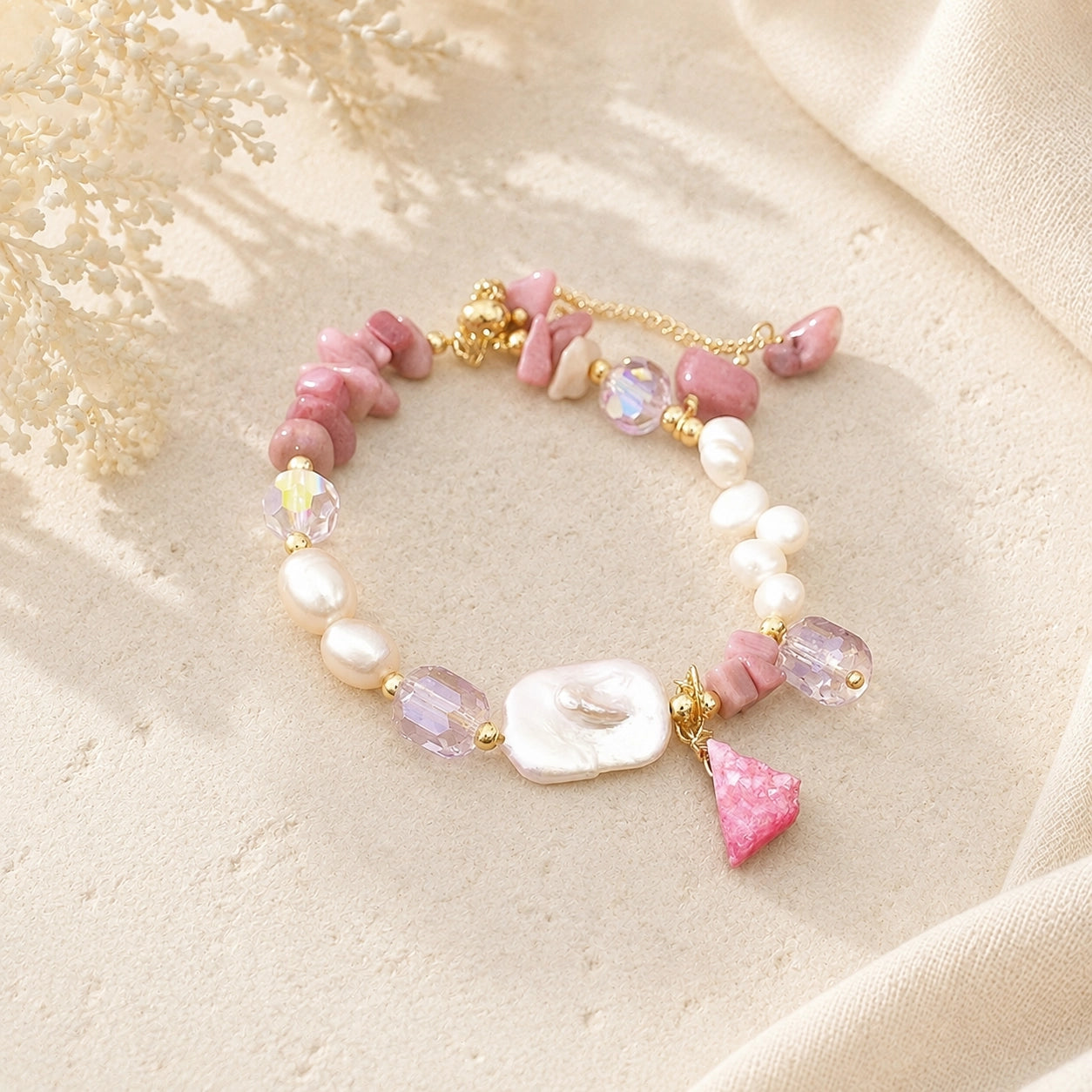 Rhodonite chip and baroque freshwater pearl bracelet with a pink stone charm styled on cream stone
