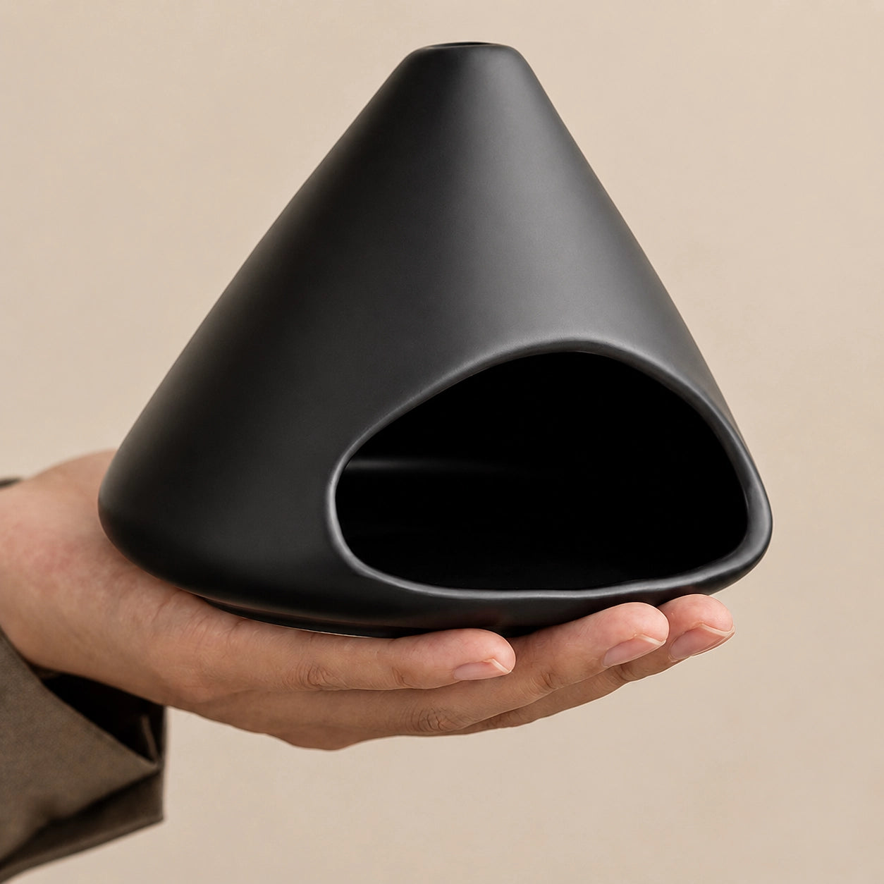 Hand holding a matte black ceramic Palo Santo and sage burner with an open front chamber and top smoke vent