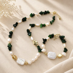 Green jade and freshwater pearl necklace and bracelet displayed together on soft cream fabric