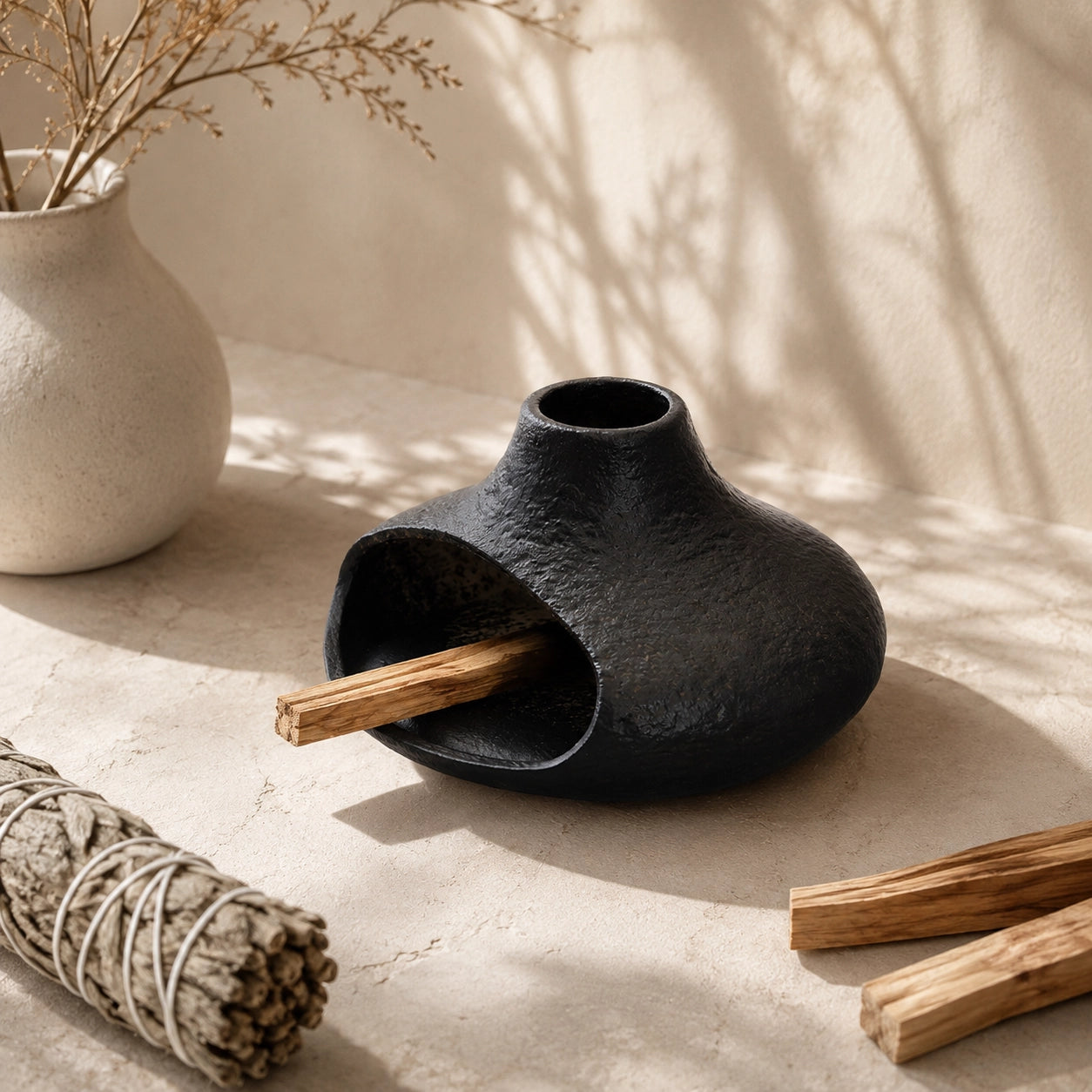 Black chimney-style ceramic Palo Santo holder styled with sage and wood sticks