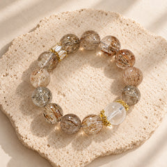 Black Golden Super Seven and clear quartz bracelet with warm amber-toned beads and gold-plated details.