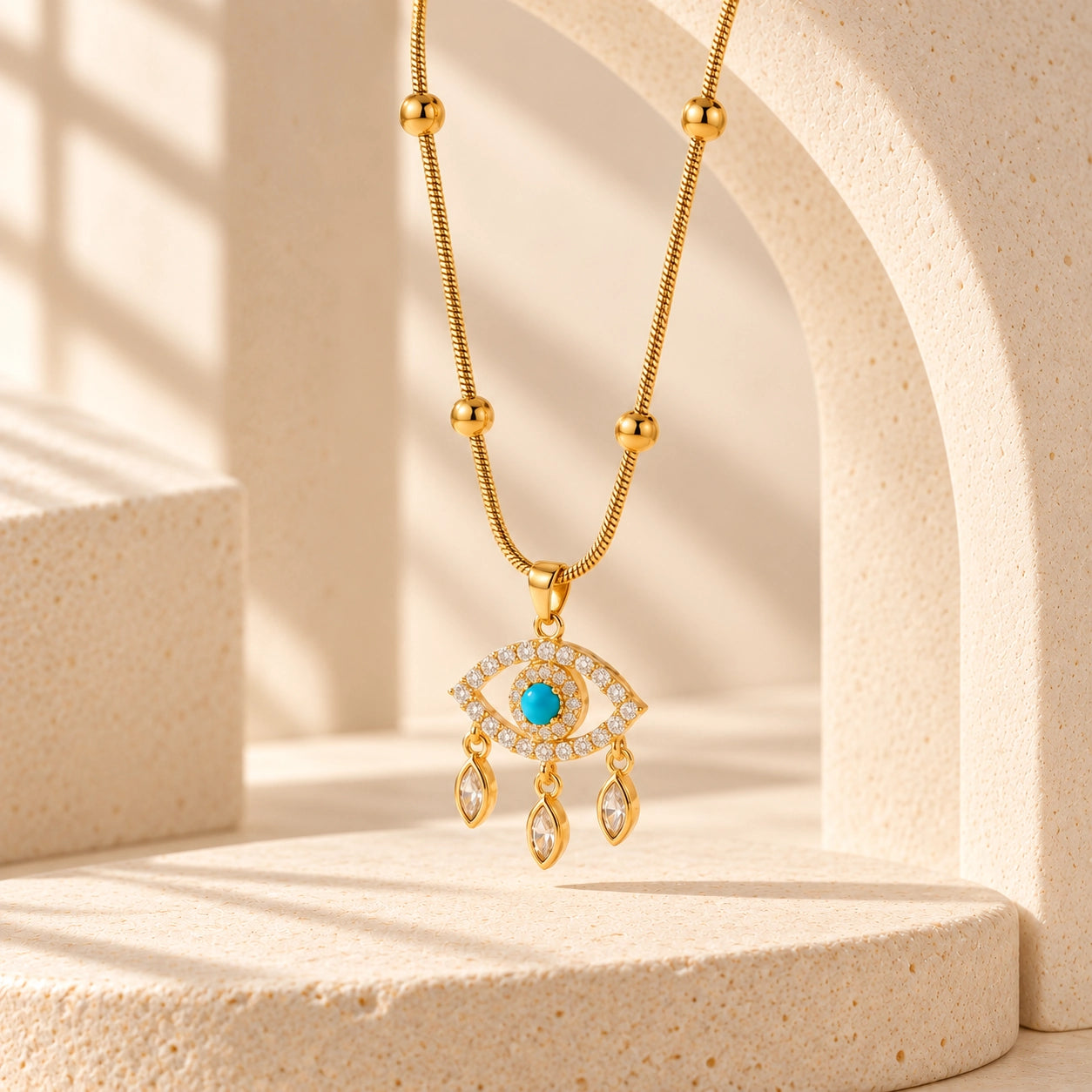 Gold-tone blue evil eye necklace suspended against an ivory stone arch in warm natural light