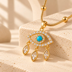 Close-up of blue evil eye pendant with sparkling clear accents and three dangling marquise charms