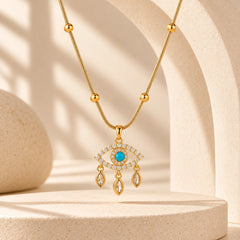 Blue evil eye pendant necklace with gold-tone bead chain displayed in a warm ivory stone arch