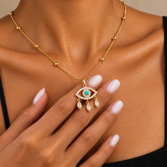 Model gently holding blue evil eye pendant to show the necklace's delicate size and charm details
