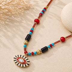 Close-up of enamel Evil Eye pendant with red, turquoise, black and gold-tone gemstone beads