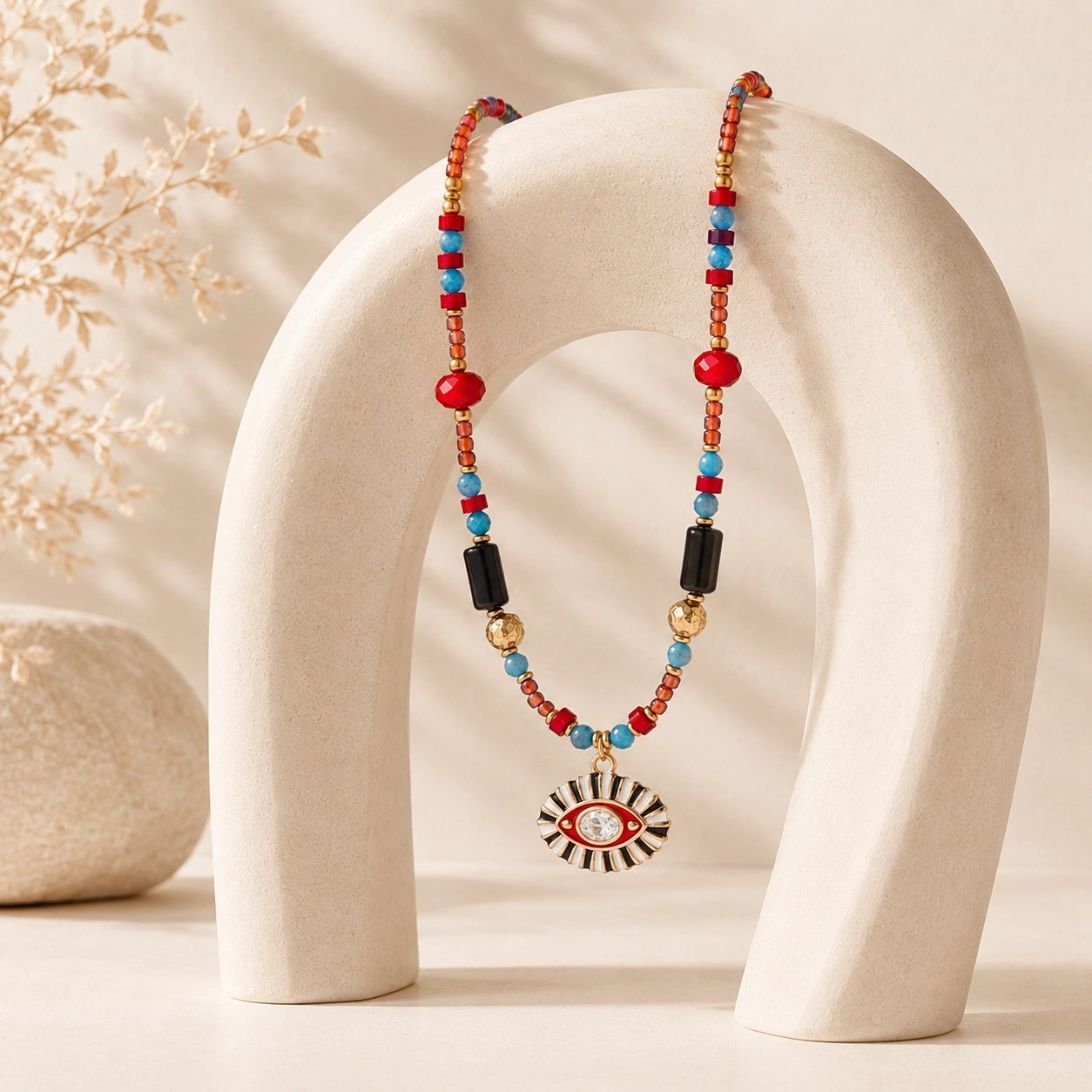Colorful Evil Eye gemstone necklace draped over a sculptural cream jewelry stand