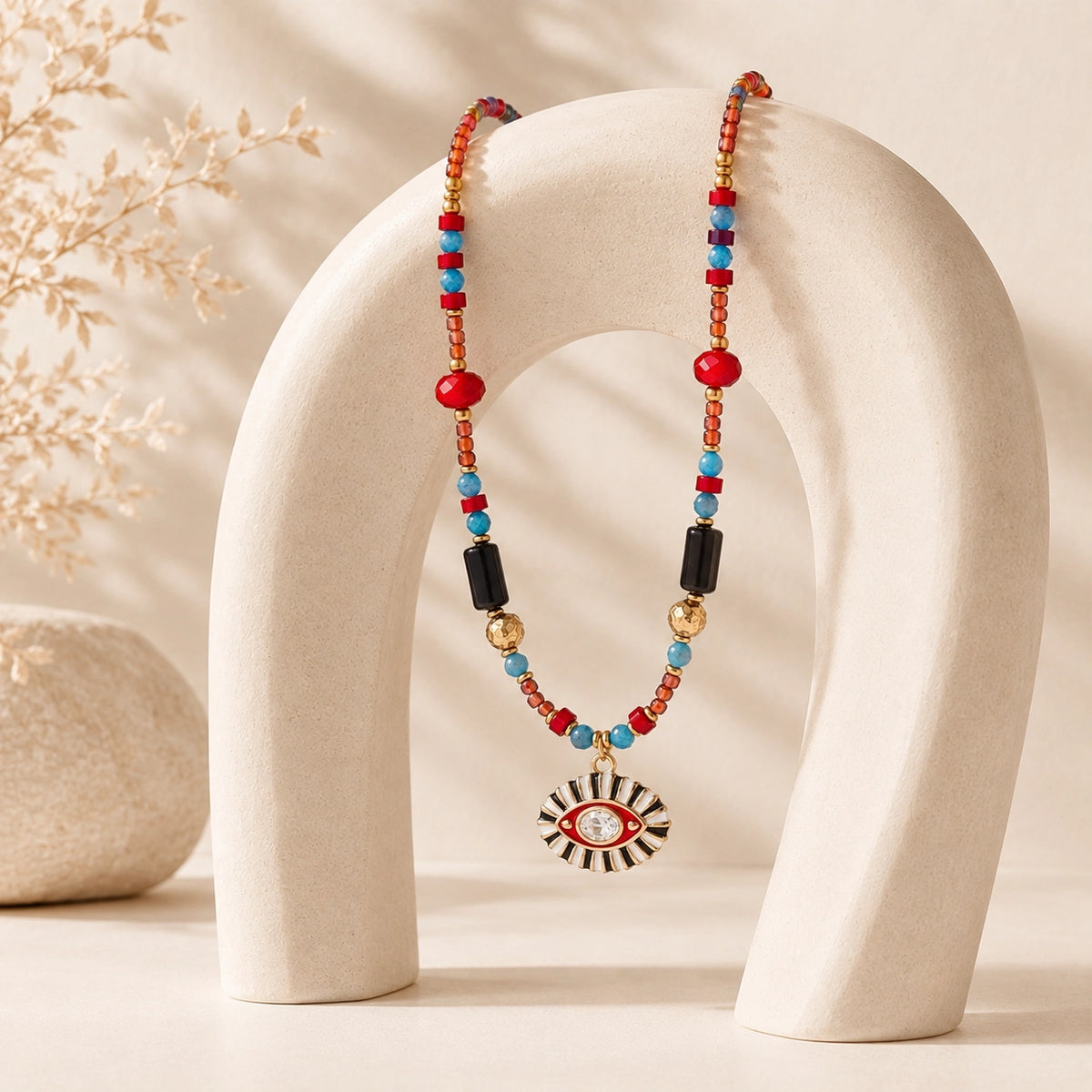 Colorful Evil Eye gemstone necklace draped over a sculptural cream jewelry stand