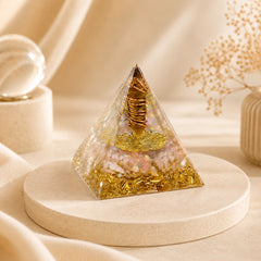 Tiger’s eye and citrine orgonite pyramid with copper coil and gold details styled as meaningful crystal decor on a soft beige display