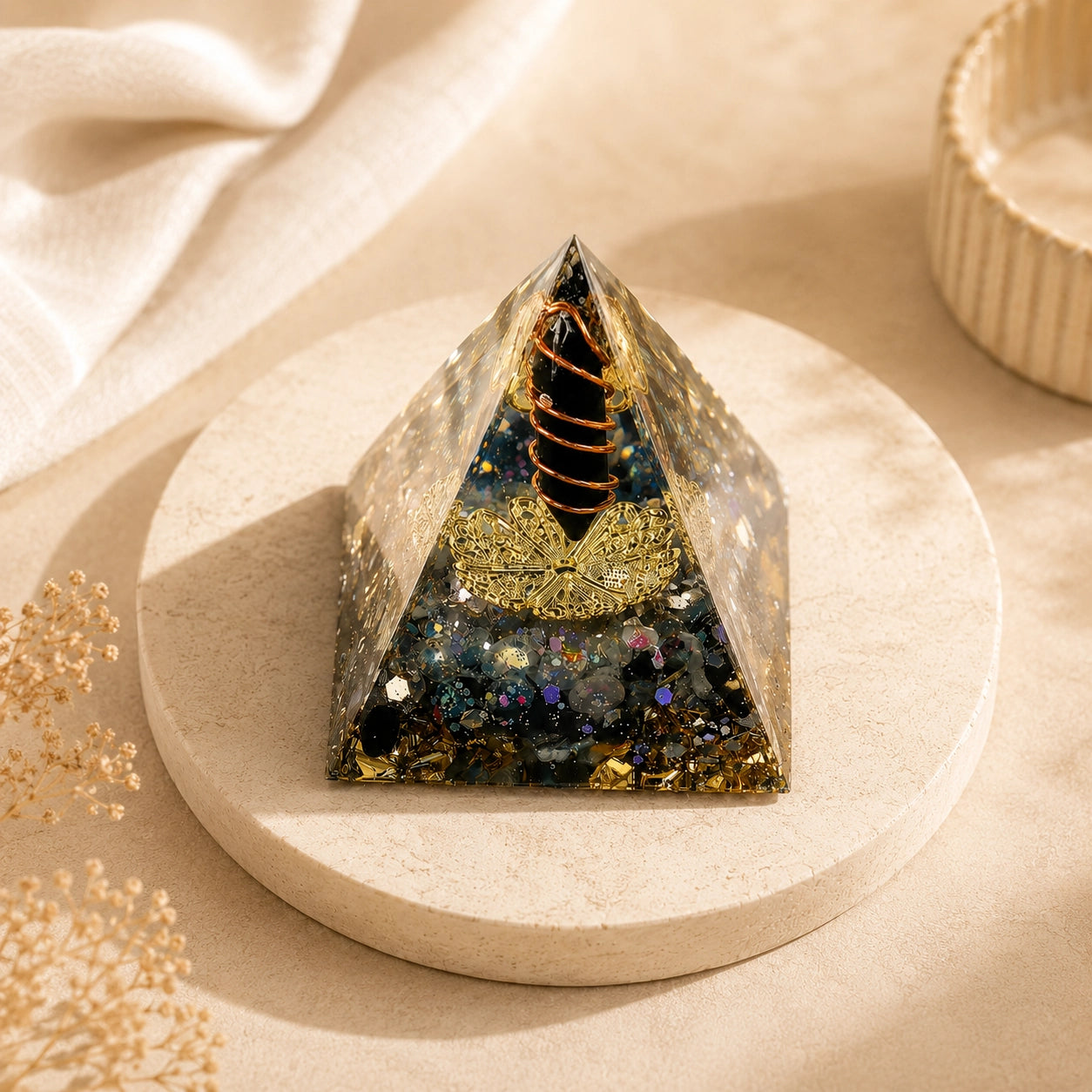 Protection & Energy Shield orgonite pyramid with obsidian, labradorite, copper coil, and gold foil on a warm neutral display stand