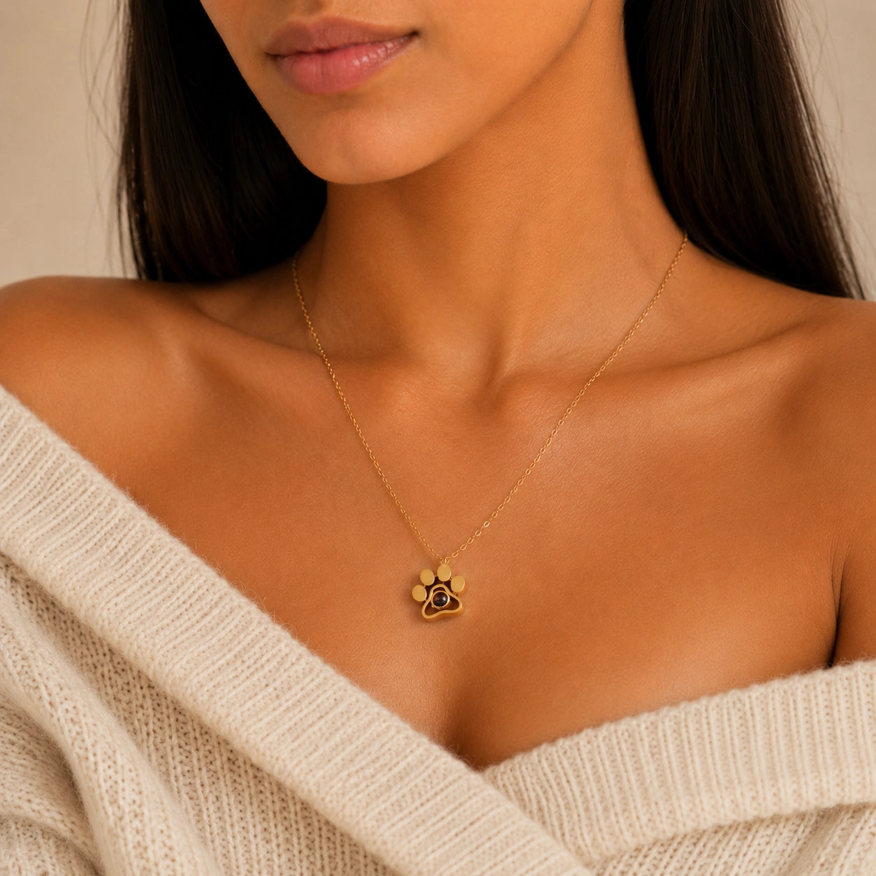 Woman wearing a gold personalized pet photo projection necklace with a small paw print pendant