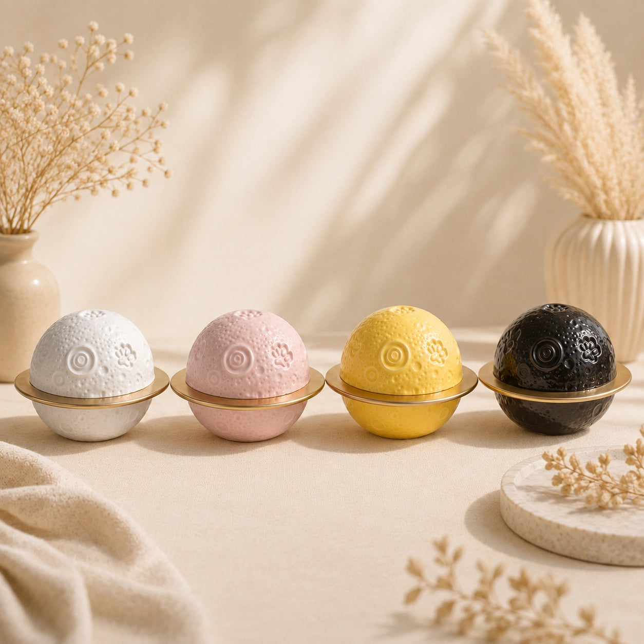 Four planet-shaped ceramic pet urns in white, pink, yellow and black