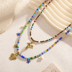 Angel and sea turtle beaded necklaces with gold charms on a neutral background