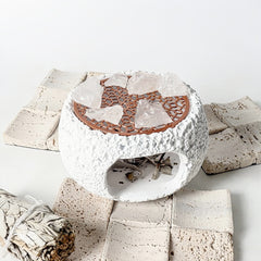 White ceramic smudge bowl with ventilation grid and raw rose quartz chunks
