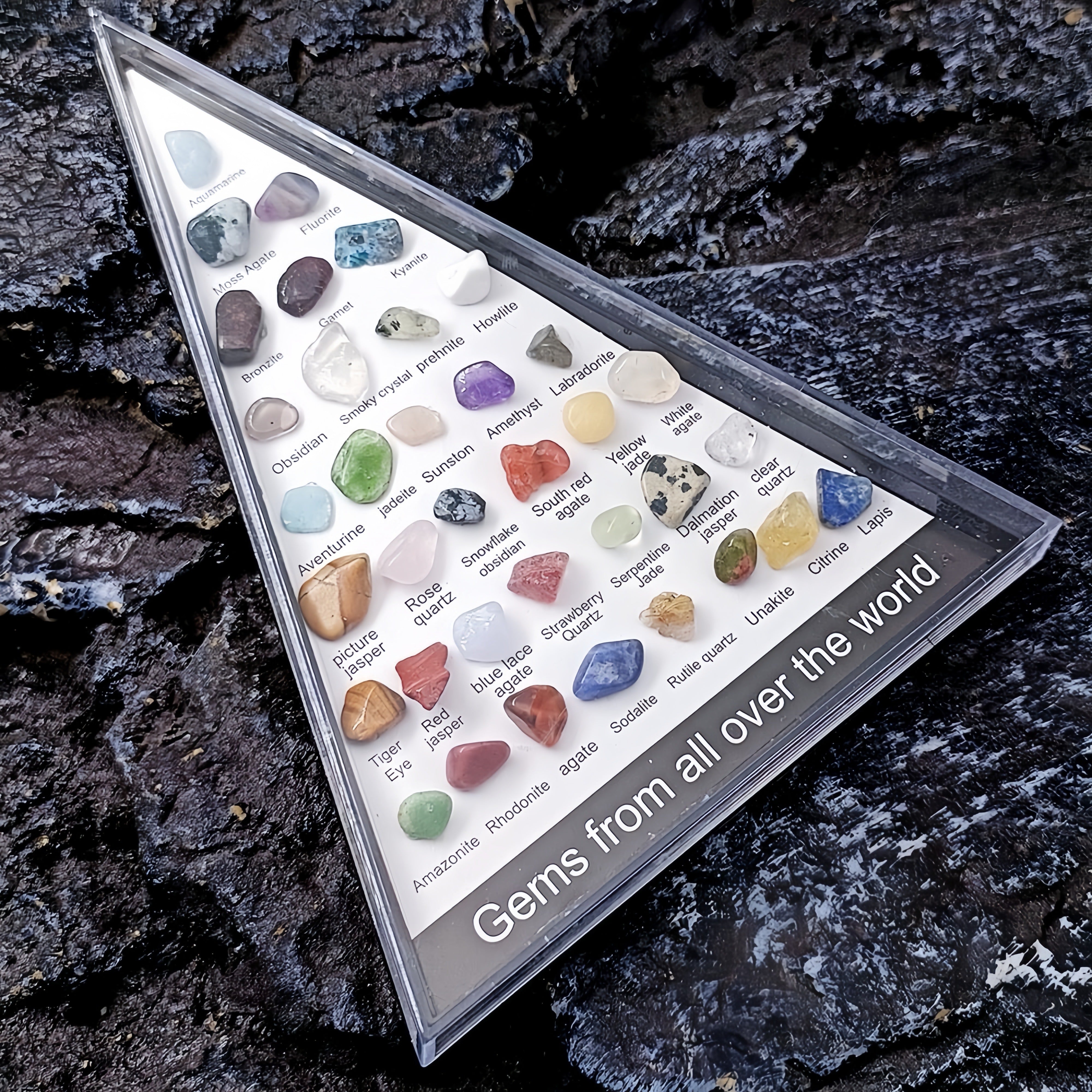 Collection of gemstones in a display case on a dark stone background