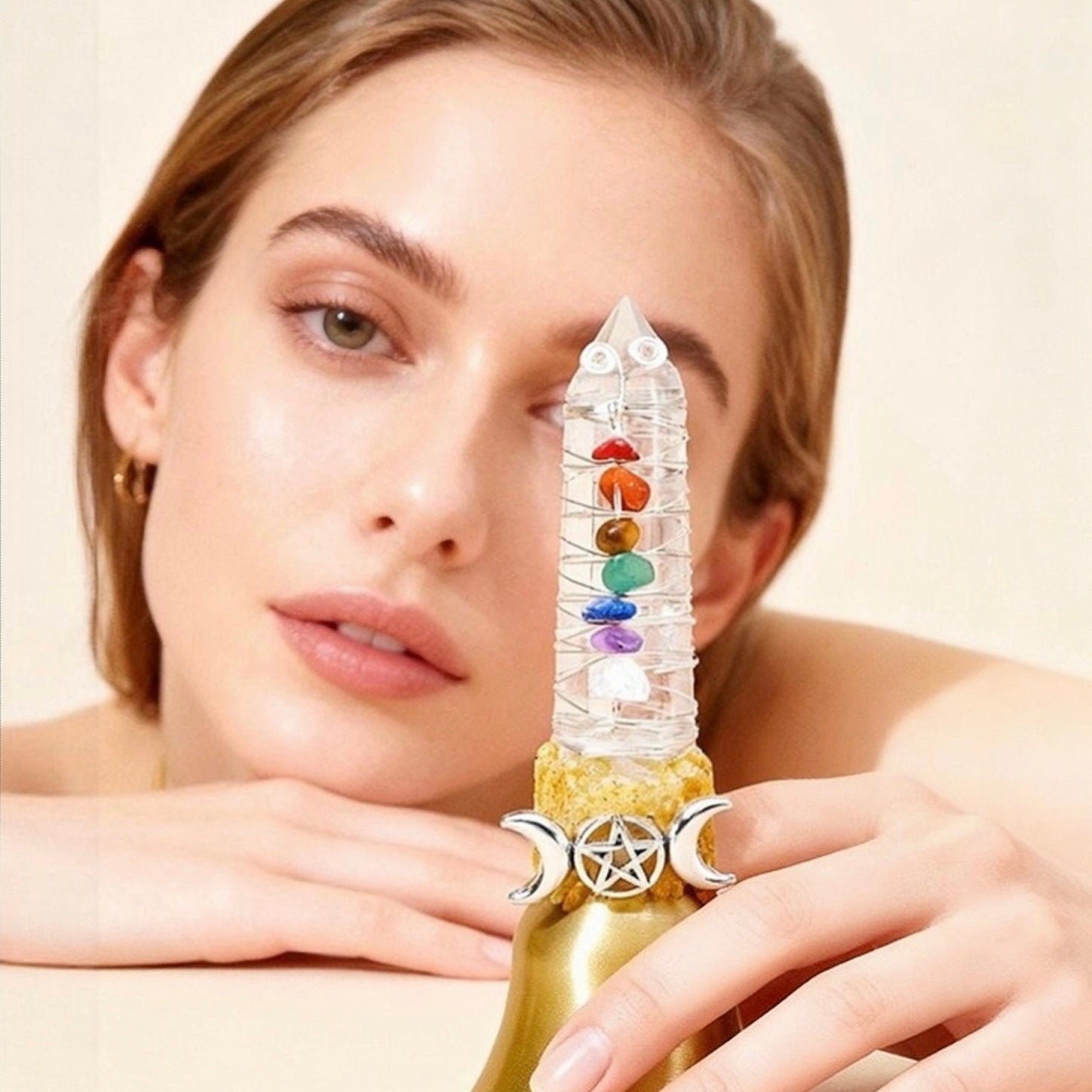 Crystal point bell tower with chakra colors held by a person against a neutral background