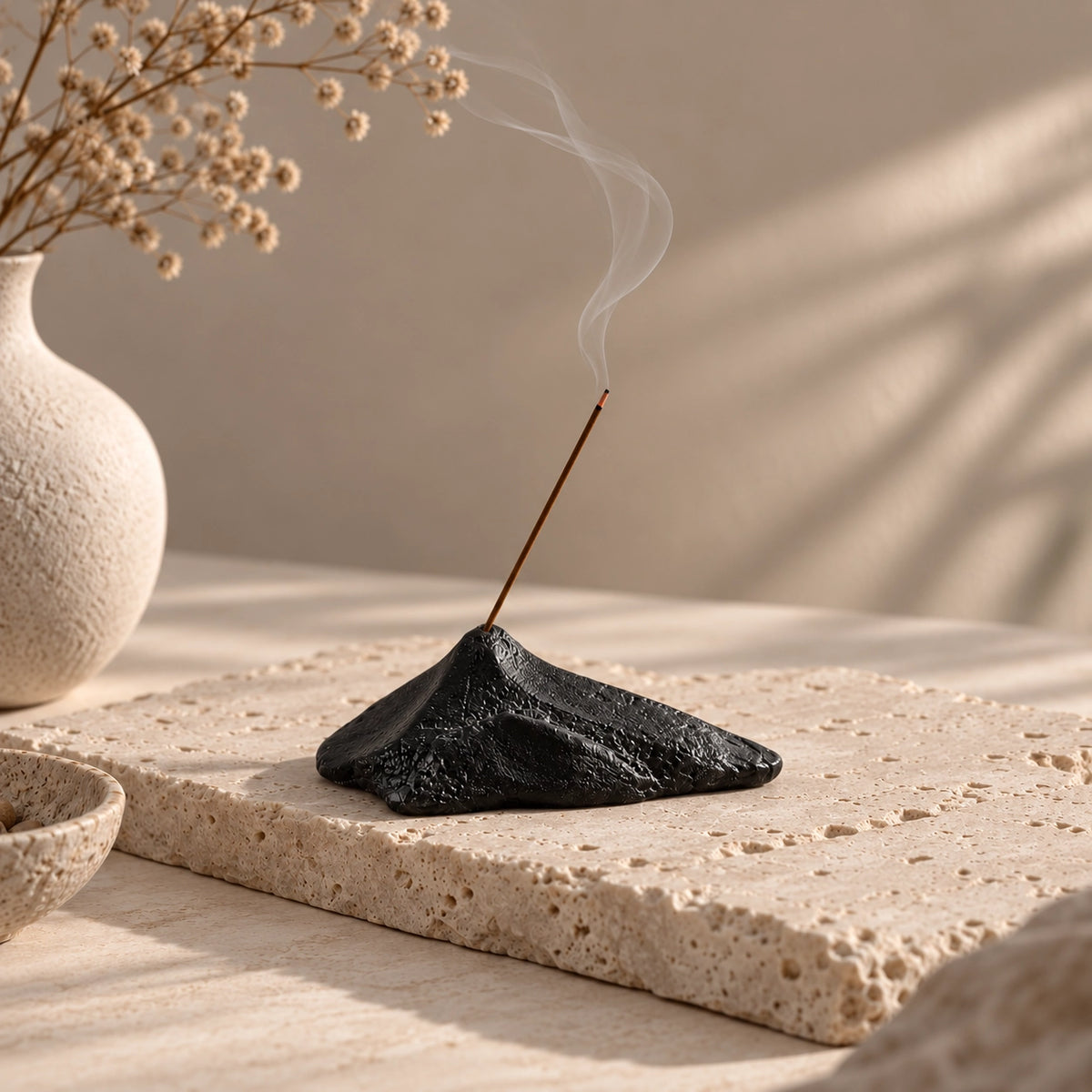 Black sculptural mountain incense stick holder with smoke in a warm Wabi-Sabi interior