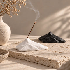White mountain-shaped ceramic incense stick holder with black option in the background in a Wabi-Sabi setting
