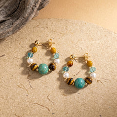 tiger eye and turquoise hoop earrings with colorful gemstone beads on textured stone background